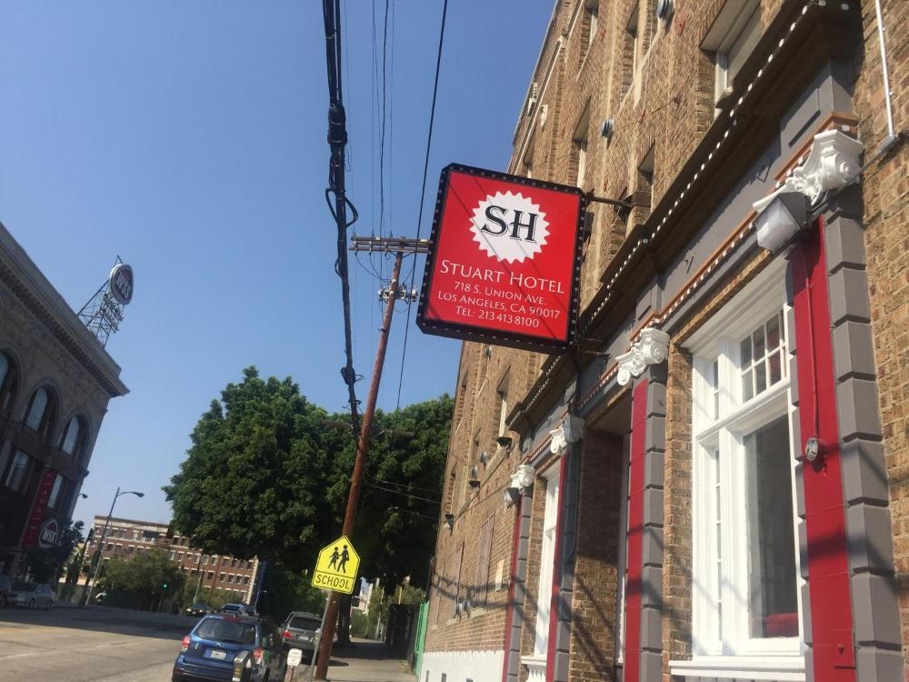 A brick building with a red sign and a white window frame on a street corner.